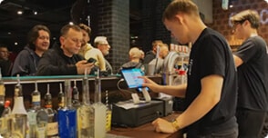 Barman obsługujący klientów w barze za pomocą systemu POSbistro, który wspiera w efektywnym zarządzaniu sprzedażą i personelem.